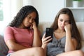 Two bored roommates checking phone content Royalty Free Stock Photo