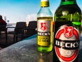 Two bottles of becks beer on a table with a blue sky in the background