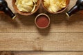 Two Bottles of beer with chips and  tomato ketchup on  wooden background Royalty Free Stock Photo