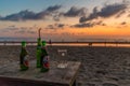 Two bottles of beer & pint glass on wooden table on Seminyak beach at sunset in Bali, Indonesia, Asia Royalty Free Stock Photo