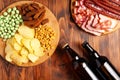 Two bottles of beer and a variety of snacks for every taste on a wooden background. Meat products, sausage slices, chips, nuts,