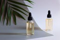 Two bottles of cosmetic essential oil and palm leaf. Beauty and body care concept. Serum skin care and anti-aging