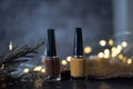 Two bottles of dark brown nail polish, brown tones on a black, gray background with dark green leaves. the back is fire slightly Royalty Free Stock Photo