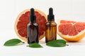 Two bottles of droppers with cosmetic grapefruit oil or facial serum against the background of fresh grapefruit fruit. a natural Royalty Free Stock Photo