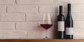 two bottles and glass of red wine on a white brick wall background. Copy space Royalty Free Stock Photo