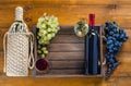 Two bottles with glasses of wine and grapes on a wooden background. Royalty Free Stock Photo