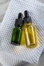 Two bottles of green natural serum and yellow organic beauty face oil for cosmetic anti age treatment skin care on towels and