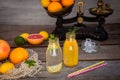 Two bottles with homemade lemonade and orange fresh juice with mint and ice on the rustic wooden background with fresh citrus in Royalty Free Stock Photo