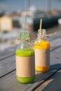 Two bottles of juice or smoothies stand on a wooden table or background. Orange and kiwi juice. Fruit cocktails in a Royalty Free Stock Photo