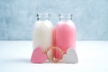 Two bottles of milk drink of different colors and two tied hearts symbolize a couple in love. Royalty Free Stock Photo
