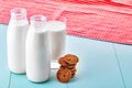 Two bottles of milk, a glass full of milk, chocolate chip cookies and a tablecloth on blue wooden table. Royalty Free Stock Photo