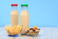 Two bottles of milk with red and green cap and bowls with muesli and cornflakes