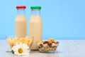 Two bottles of milk with red and green cap and bowls with muesli and cornflakes