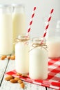 Two bottles of milk with striped straws and almonds on the white wooden background Royalty Free Stock Photo
