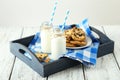 Two bottles of milk with striped straws and plate of cookies on the white wooden background Royalty Free Stock Photo