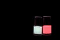 Two bottles of pink and mint color nail polish isolated on black. Beauty concept. Top view, copy space Royalty Free Stock Photo