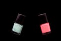 Two bottles of pink and mint color nail polish isolated on black. Beauty concept. Top view, copy space Royalty Free Stock Photo