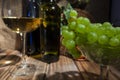 Two bottles of red and white wine on a wooden table with a bunch of grapes and a glass on a thin stem Royalty Free Stock Photo