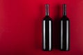 Two bottles of red wine on a red background. Romantic mood. Space for text Royalty Free Stock Photo