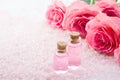 Two bottles with rose oil, spa salt crystals and pink roses