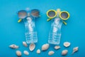 two bottles of water on a blue background are like people on vacation, bottled glasses, beside scattered seashells, concept Royalty Free Stock Photo