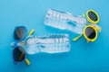 Two bottles of water lie on a blue background, like people sunbathing in the sun, bottles of blue and yellow glasses, concept Royalty Free Stock Photo