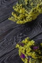 Two bouquets of statice. One is yellow, the other is multi-colored. Against the background of pine boards