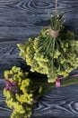 Two bouquets of statice. One is yellow, the other is multi-colored. Against the background of pine boards