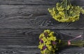 Two bouquets of statice. One is yellow, the other is multi-colored. Against the background of pine boards