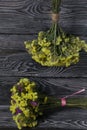 Two bouquets of statice. One is yellow, the other is multi-colored. Against the background of pine boards