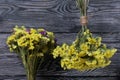 Two bouquets of statice. One is yellow, the other is multi-colored. Against the background of pine boards