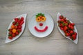 two bowl of fresh red strawberries and apricots and water melon on the table and fruit smile