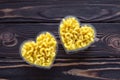 Two bowl of heart with yellow raw pasta on dark wooden boards, timber background. Laconic design, minimalist style. Symbol of love