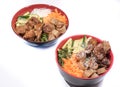 Two bowls of beef Bo bun with salad, pork ribs, fresh herbs