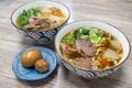 Two bowls of beef noodle soup, an egg and a meatball on wooden table Royalty Free Stock Photo