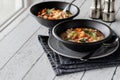 Two bowls of chicken and vegetable couscous soup against a sunny window.