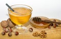 Two bowls with dark and light honey, hazelnuts, walnuts on wooden table with white background