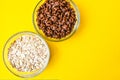 Two bowls with quick breakfast of chocolate cornflakes and oat meal on bright yellow baclground. Copy space Royalty Free Stock Photo