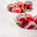 Bowls with red ripe sweet cherries with water drops on white background Royalty Free Stock Photo