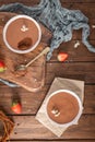 Two bowls of smooth chocolate mousse, garnished with delicate white flowers, are presented on a rustic wooden table with a silver Royalty Free Stock Photo