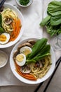 Two bowls with vegan soup with noodles, vegetable broth, mushrooms, eggs, carrots. Top view, assian food. Royalty Free Stock Photo