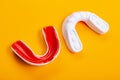 Two boxing mouthguards, red and white, lie on a yellow background, concept, diagonal arrangement Royalty Free Stock Photo