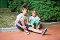 Two boy brothers single-breasted homeless homeless sit on the curb in the late evening.