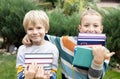 Two boy friends stand next to each other and hold stacks of books in front of them Royalty Free Stock Photo