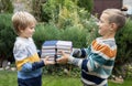 Two boy friends stand opposite each other and hold stacks of books in front of them Royalty Free Stock Photo