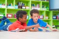 Two boy kid lay down on floor and reading tale book in preschoo Royalty Free Stock Photo