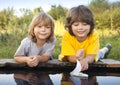 Two boys allowed paper boats from the pier of the river Royalty Free Stock Photo