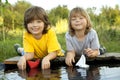 Two boys allowed paper boats from the pier of river Royalty Free Stock Photo