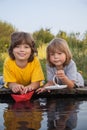 Two boys allowed paper boats from the pier of river Royalty Free Stock Photo