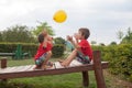 Two boys, brothers, playing with yellow balloon in the park